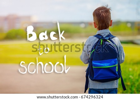 Child going back to school with backpack on green nature background with text Back to school. Back view.