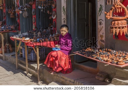 BHAKTAPUR, NEPAL - DEC 2, 2013: an unidentified little girl sitting that sells products of pottery in a stall on December 2, 2013 in Bhaktapur, Kathmandu Valley, Nepal