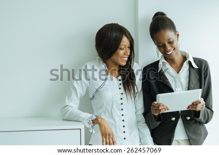 Two colleagues talking while standing about the contents on a tablet pc in a well lit office close to the window