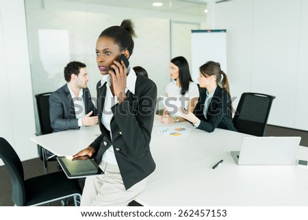 Beautiful, young, black businesswoman holding a tablet at an office meeting and getting bad news on the phone which makes her concerned and shocked