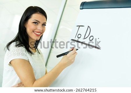 Beautiful, young, businesswoman writing To Do onto a white writing board