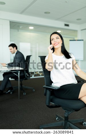 Businesswoman and a businessman working in an nice office  while sitting in chairs at their desks