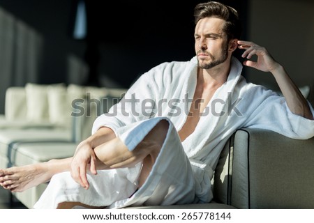 Young, handsome man in the morning thinking while sitting in a hotel room in a robe