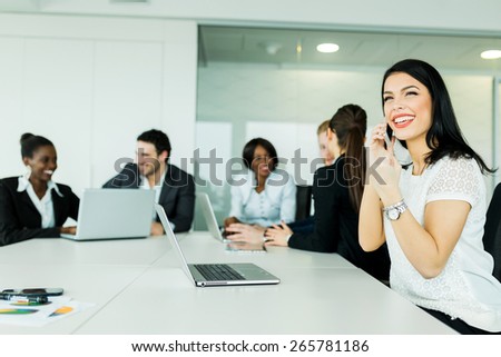 Beautiful young businesswoman receiving good news on the phone with her smile hinting at future fruitful business deals
