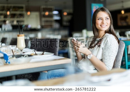 Beautiful lady sitting in a bar and smiling while holding cell phone