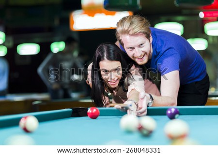 Young handsome man and woman flirting while playing billiard