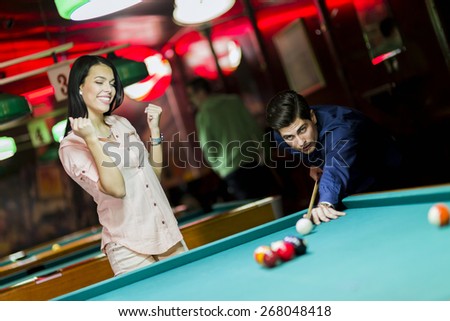 Young people playing billiard in a club pub bar