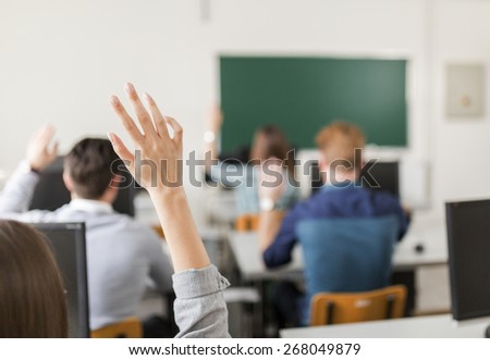 Young students raising hands in a classroom showing they are ready
