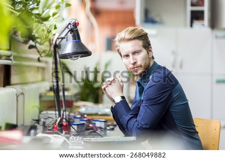 Young handsome man thinking how to solder the circuit board and fix it