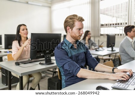 Young handsome student using computer in classroom