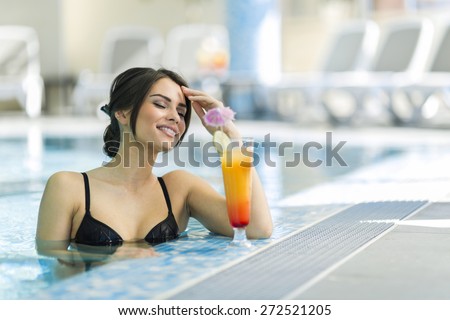 Beautiful lady drinking a cocktail in a swimming pool and relaxing