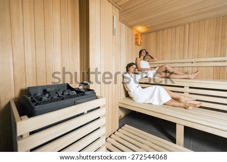 Sauna heater in a cozy sauna and girls relaxing in the background
