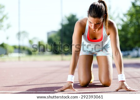 Beautiful female sprinter getting ready for the run during summer