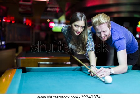 Young handsome man and woman flirting while playing billiard