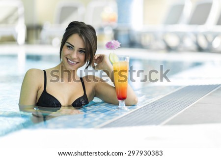 Beautiful lady drinking a cocktail in a swimming pool and relaxing