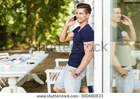 Handsome man talking on the phone outdoors and his reflection is present