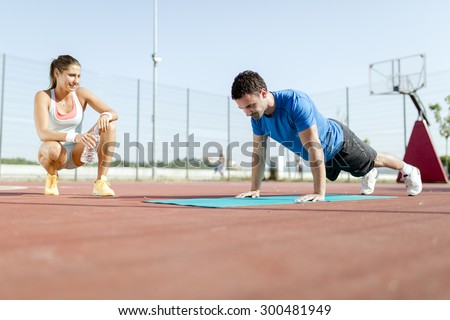 Young, beautiful, fit and healthy personal trainer counting push-ups and motivating