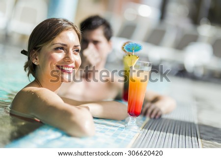 Young people drinking cocktails by the swimming pool and relaxing