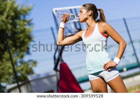 Young beautiful athlete drinking water after exercising to revitalize
