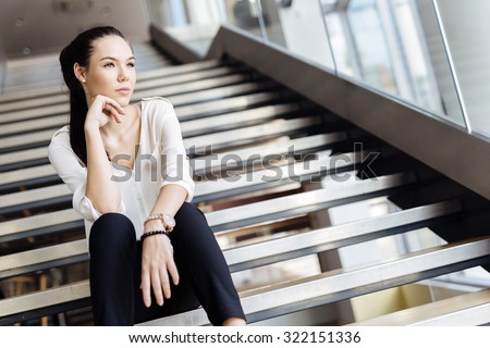 Businesswoman sitting on stairs and thinking. Fashion style photo