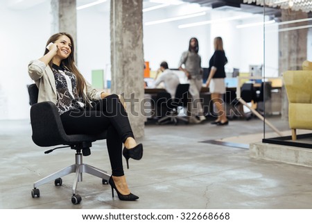 Confident business woman using phone in an office