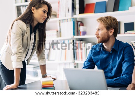 Beautiful female colleague asks question in office from her coworker