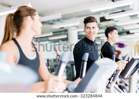 Handsome man and beautiful young woman using a stepper in a gym and having a conversation