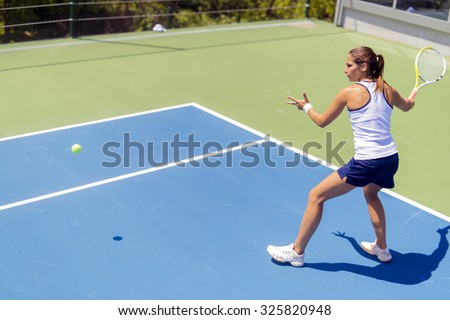 Beautiful female tennis player in action, hitting a forehand