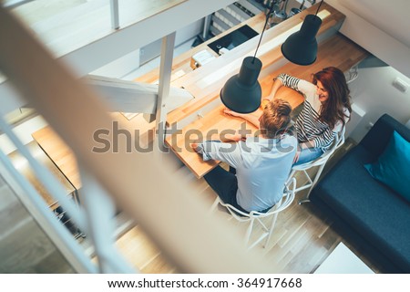 Beautiful couple talking in their pristine home while sitting at kitchen counter