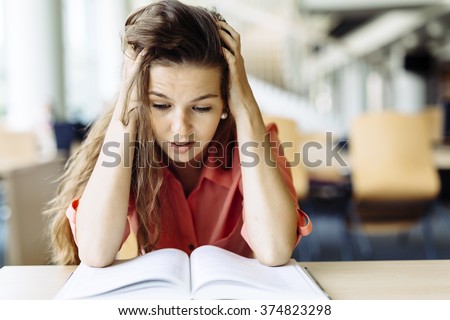 Female student studying and reading in a library but is having a hard time understanding the material