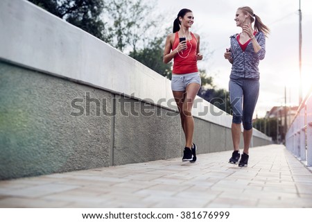Beautiful scenery of two female joggers pursuing their activity outdoors in the city in dusk