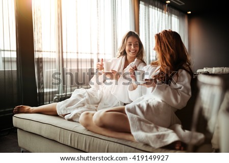 Women relaxing and drinking tea in robes during wellness weekend