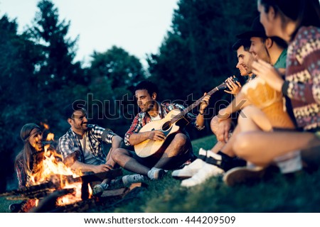 Friends enjoying music near campfire at night