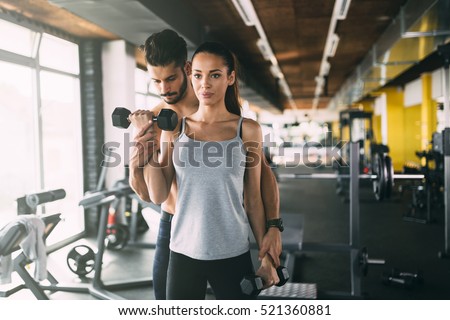 Personal trainer helping woman in gym