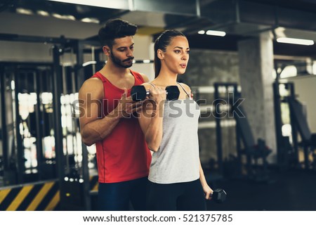 Personal trainer instructing trainee in gym
