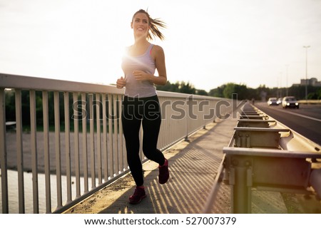 Happy sporty woman jogging outdoors