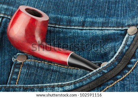 Smoking pipe in blue jeans pocket. Old Style concept.