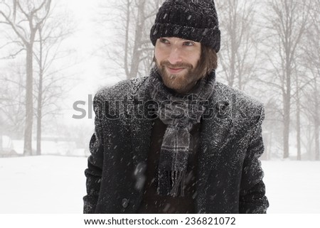 Fashionable man looking off in the distance during a snow storm.