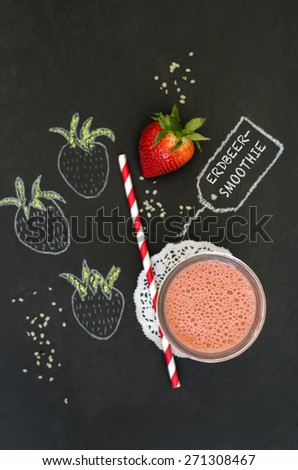 Strawberry smoothie on blackboard with fresh fruit and chalk painted strawberries
