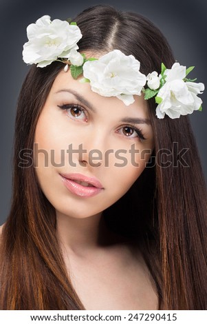 Beauty face of the young beautiful woman with white flowers in her hair. Fashion model with hairstyle and flowers in her hair