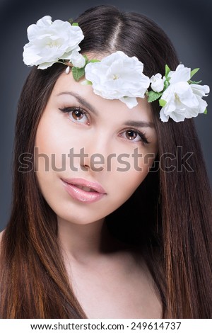 Beautiful woman with long healthy hair and perfect clean skin studio portrait. Beauty face of the young beautiful woman with white flowers in her hair.
