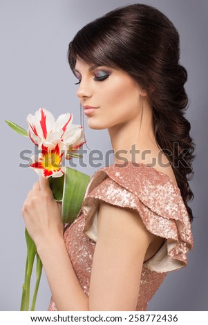 Spring beauty model studio shooting. Portrait of smiling young woman with flowers orange tulips on white background. Fashion fresh makeup. Sensual lips. Perfect skin. Tenderness. Romantic style.