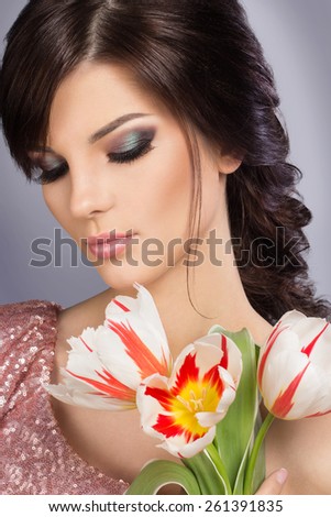 Spring beauty model studio shooting. Portrait of smiling young woman with flowers orange tulips on white background. Fashion fresh makeup. Sensual lips. Perfect skin. Tenderness. Romantic style.