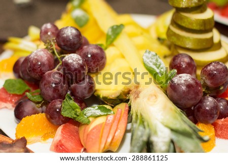 Mixed fruit platter. Variety of fruit on a plate includes grapes, pear, melon, raspberry, mango, pineapple, grapefruit, tropical, juicy, fresh, healthy