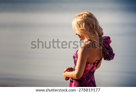 portrait of blonde longhaired girl in red dress half back-view