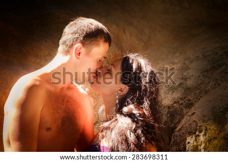 woman and man kiss in cave at front sun rays