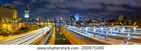 Panoramic cityscape of Tel Aviv city at night with an intensive traffic on highway, central rail station, river and skyscrapers of  business center. Long exposure tripod shot, patchwork landscape.