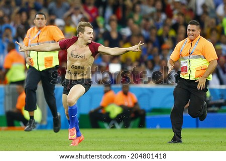 RIO DE JANEIRO, BRAZIL - July 13, 2014: Security personnels chase a pitch invader during the 2014 World Cup Final game between Argentina and Germany at Maracana Stadium. NO USE IN BRAZIL.