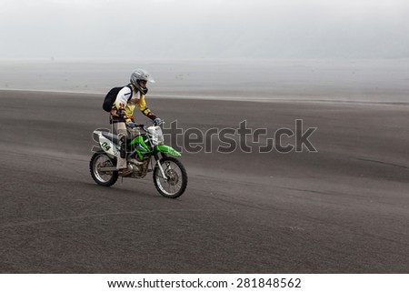 JAVA, INDONESIA - Apr 19, 2015: Tourist riding offroad bike through black ash sand dunes in Bromo Tengger national park at Java island in Indonesia.