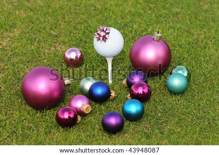 Golferâ??s Christmas with assortment of ornaments surrounding and on a Golf Tee.  Focus is on the ornament on the golf tee.